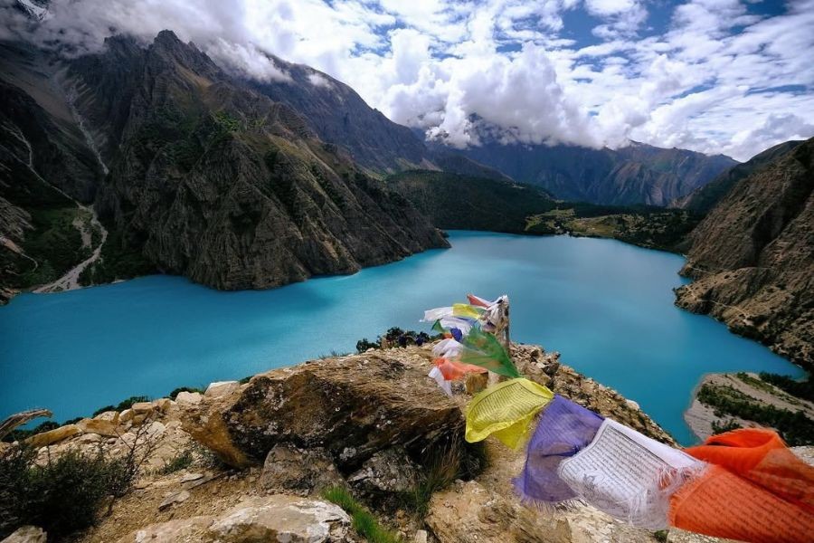 Phoksundo Lake's striking turquoise water with colorful prayer flags